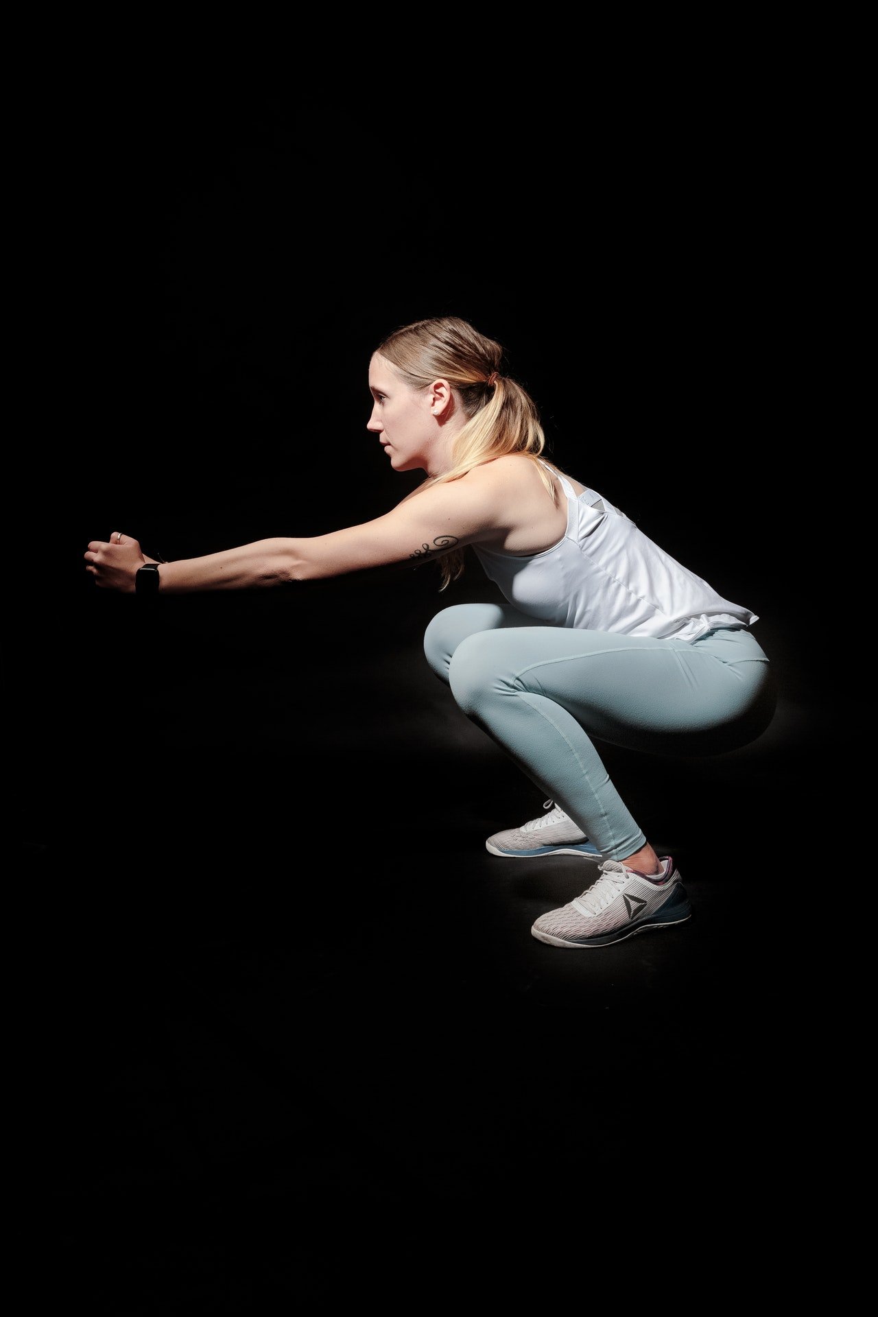 side-view-photo-of-woman-doing-squats-against-black-2417485